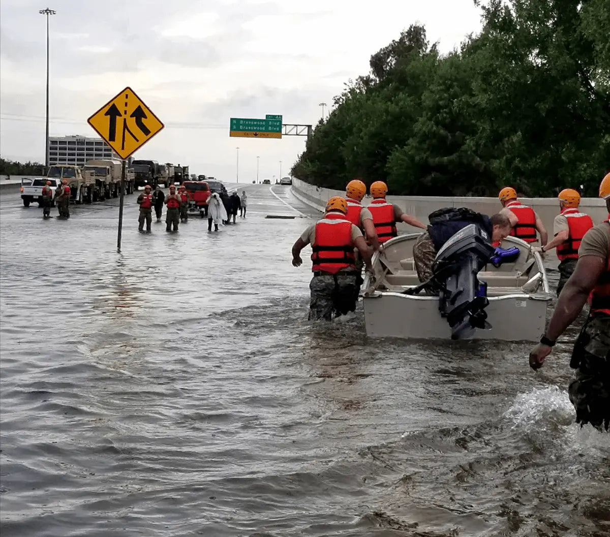 Protective team escorting a performer through a crowd at an outdoor event with crowd control barriers on both sides.